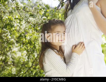 Glückliche schwangere Mutter und ihre kleine Tochter in den Frühling Stockfoto