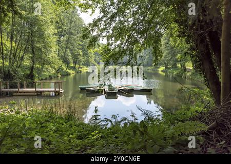 Ruderboote auf einem Bergsee mit Holzsteg in einem bewaldeten Tal Stockfoto