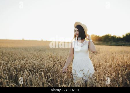 Mädchen im Weizenfeld, Mädchenhand und Weizenspikelett, Sonnenuntergang auf dem Feld. Stockfoto