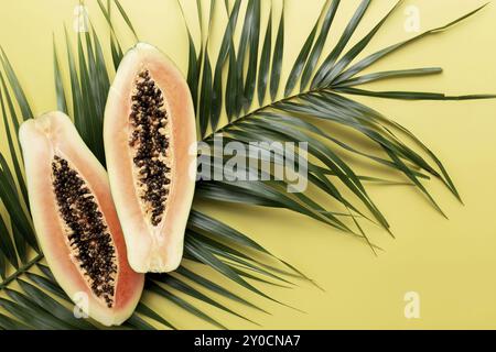 Frische tropische Papaya-Fruchthälften auf dem Palmblatt Ein gelber Hintergrund Draufsicht flach lag für einige Werbung Text Stockfoto