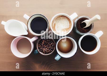 Mehrere Kaffeetassen und bunte Tassen mit Americano, Espresso, Latte und Cappuccino, Milchglas, geröstete Kaffeebohnen in Glasflasche, Holzlöffel Stockfoto