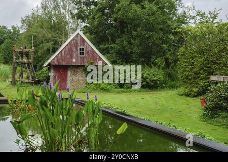 Idyllische Szene mit einer kleinen roten Scheune, einem Teich und umgebender Vegetation in einer ländlichen Gegend, Aalten, gelderland, niederlande Stockfoto