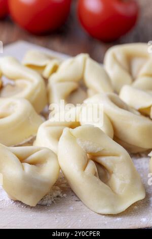 Rohe Tortellini auf Holz mit Tomaten Stockfoto