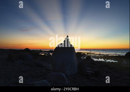 Steinpyramide an der Ostsee mit Blick auf das Meer bei Sonnenuntergang. Die Sonne scheint hinter der Steinpyramide. Steine als Silhouette. Spirituelle Sichtweise. Querformat f Stockfoto