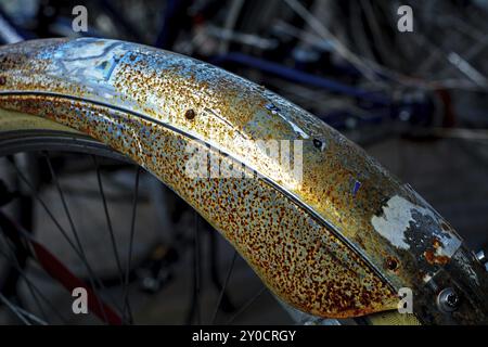 Rost und Überreste von Aufklebern auf einem Radschutz, abstrakter dunkler Hintergrund mit heller Diagonale, Detail mit schmaler Schärfentiefe Stockfoto