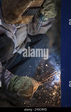 Schwere Industrie Schweißgerät Arbeiter in Schutzmaske Hand arc Schweißbrenner arbeiten auf Metall Bau Stockfoto