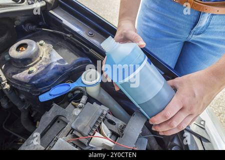 Frau Füllung Auto Reservoir mit Windschutzscheibe Wischer Flüssigkeit Stockfoto