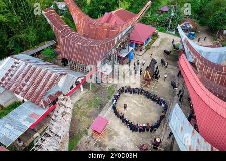 Einheimische Männer singen und tanzen in einem Kreis im Hof zwischen den traditionellen tana toraja Häusern, um ihre Vorfahren Sulawesi zu ehren Stockfoto