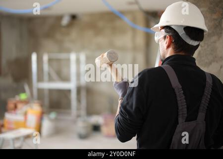 Rückansicht eines Bauarbeiters mit Vorschlaghammer-Reformierhaus Stockfoto