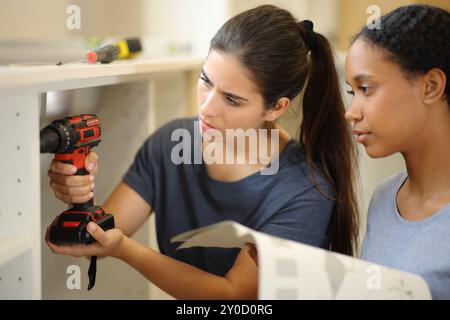 Interrassische Mitbewohner installieren Möbel in der Küche mit Anleitung Stockfoto