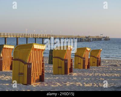 Leere Liegen stehen am Sandstrand mit Pier und ruhigem Meer unter klarem Himmel, binz, rügen, ostsee, deutschland Stockfoto