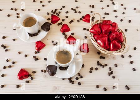 Rot Schokolade Herzen in einem kleinen Korb und zwei Tassen Kaffee mit Kaffeebohnen gesehen von oben Stockfoto