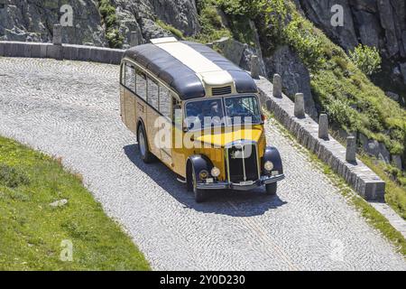 Der historische postbus fährt entlang der Tremola, der weltberühmten Serpentinenstraße durch das Val Tremolo. Touristenbus auf der Tremola-Straße, Schweiz Stockfoto