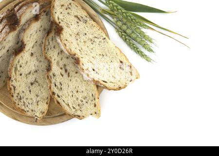 Geschnittenes Weizenbrot mit gesprochenem Roggen in der Nähe von jungen Weizenohren isoliert auf weißem Hintergrund. Brotscheiben in einer niedrigen Ansicht Stockfoto