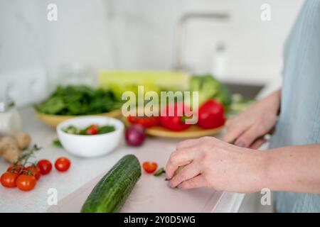 Eine Frau wird von oben gesehen, die eine Gurke in einer Mischung aus frischem Gemüse schneidet Stockfoto