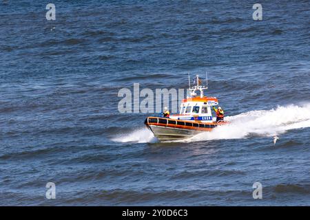 Ein Rettungsboot der niederländischen Küstenwache (Reddingsbrigade KNRM) rastet durch abgehacktes Wasser und hinterlässt einen weißen Schaumstoffpfad. Stockfoto