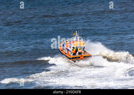 Ein Rettungsboot der niederländischen Küstenwache (Reddingsbrigade KNRM) rastet durch abgehacktes Wasser und hinterlässt einen weißen Schaumstoffpfad. Stockfoto