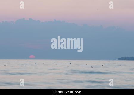 Sonnenuntergang am Strand in der Nähe der Stadt Vlorë in Albanien, die sich an der Bucht von Vlorë ausbreitet und von den Ausläufern der Ceraunischen Berge Ao umgeben ist Stockfoto