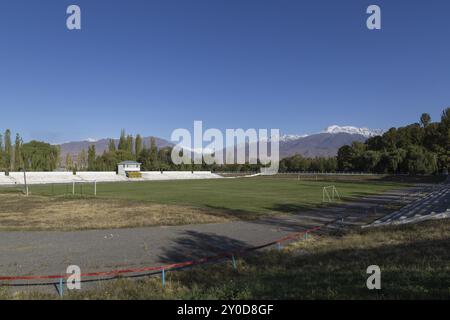 Fußballfeld und schneebedeckte Berge in Toktogul, Kirgisistan, Asien Stockfoto