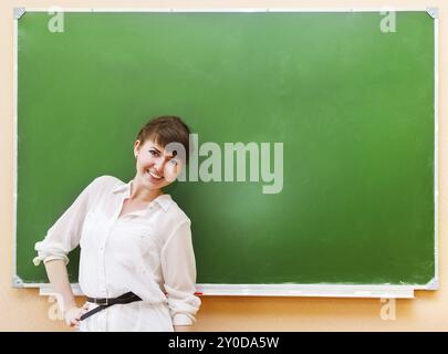 Glückliche Schüler Mädchen stehen in der Nähe von sauberen Tafel im Klassenzimmer Stockfoto