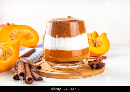 Kürbis-Gewürz-Dalgona-Kaffee-Cocktail, süßer, leckerer Herbstlatte mit Pumokinpüree, Schlagsahne und Schlagsahne-Instant-Dalgona-Kaffeeschaum Stockfoto