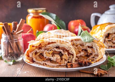 Hausgemachter herbstlicher Apfelstrudel mit karamelisierten Äpfeln, Rosinen, Nüssen, Honig, Zimtgewürzen, auf Teller auf Küchentisch Kopierraum Stockfoto