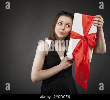 Glückliches junge Brünette Mädchen mit Geschenk dekoriert mit rotem Band Stockfoto