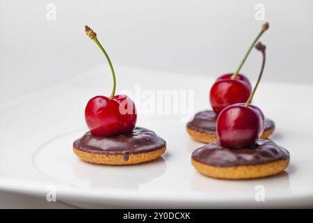 Drei Kirschen auf drei Schokoladenkeksen Stockfoto