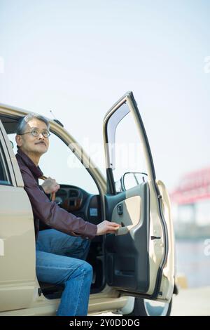 Ein älterer Mann öffnet eine Autotür Stockfoto