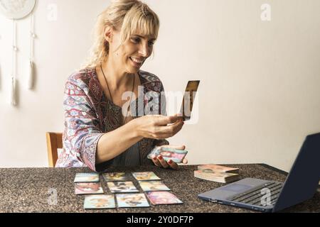 Tarot-Lesegerät zeigt den Laptop-Bildschirm mit der freigegebenen Karte während ihrer Online-Sitzung Stockfoto