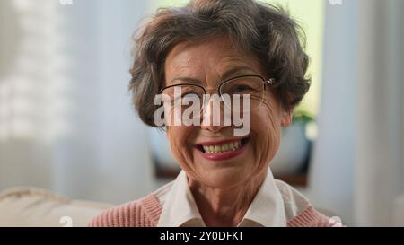 Kaukasische nachdenkliche schöne Großmutter ältere Frau blickt weg fröhliches Lächeln in der Kamera zu Hause alte reife Frau ältere Oma in Brille medizinisch Stockfoto