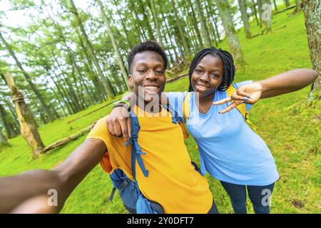 Afrikanische junge männliche und weibliche Freunde, die Spaß beim Selfie im Wald haben Stockfoto