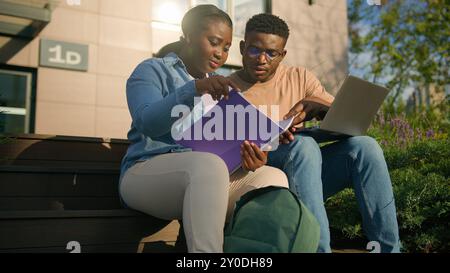 Zwei afrikanische Schüler High School Schüler Mädchen Guy auf dem College Campus draußen im Stadtpark draußen auf der Bank diskutieren Themen zusammen Aufgabe vorbereiten Stockfoto