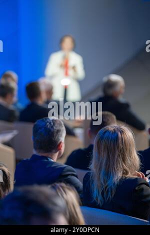 Geschäftsleute hören während der Konferenz aufmerksam dem Sprecher zu. Konzentrieren Sie sich auf das Publikum, während der Sprecher auf der Bühne vor verschwommenem Hintergrund präsentiert. Stockfoto