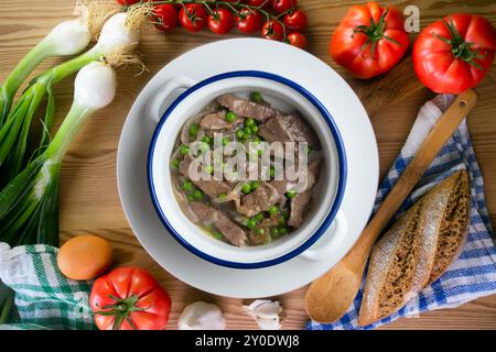 Rinderstreifen mit Zwiebeln und Erbsen gekocht. Tisch mit Draufsicht und Dekoration. Stockfoto