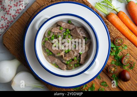 Rinderstreifen mit Zwiebeln und Erbsen gekocht. Tisch mit Draufsicht und Dekoration. Stockfoto