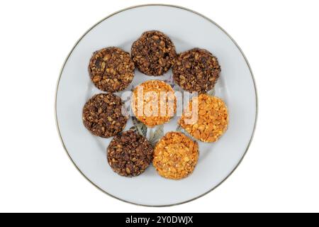 Verschiedene Kuchen in Keramikplatte isoliert auf weißem Hintergrund. Gelbe und braune romantische Kekse. Draufsicht. Stockfoto