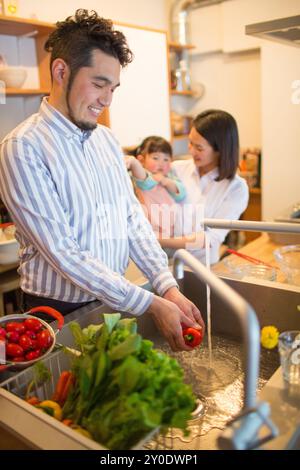 Paare mit ihrem Baby, die Salat in der Küche zubereiten Stockfoto