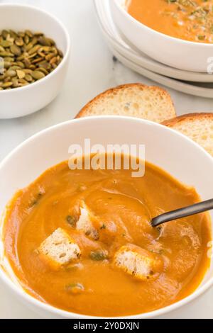 Schüssel mit Butternusskürbis-Suppe mit Croutons und Brotscheiben Stockfoto
