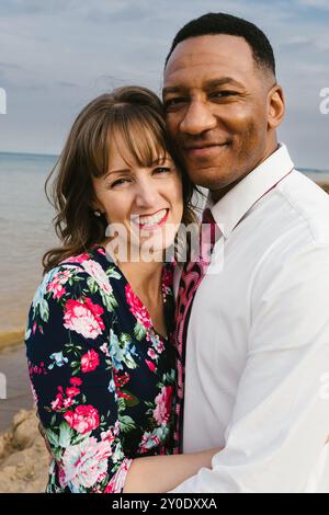 Multi Racial Paare lächeln zusammen am Strand am Wasser Stockfoto