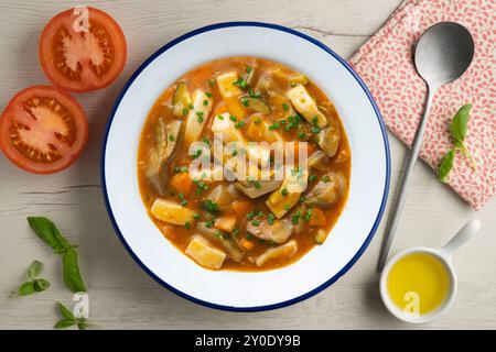 Tintenfisch-Eintopf mit Kartoffeln, Artischocken und Gemüse. Tisch mit Draufsicht und Dekoration. Stockfoto