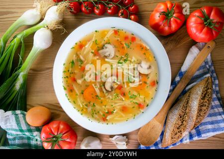 Kurze Nudelsuppe mit Gemüse und Pilzen. Tisch mit Draufsicht und Dekoration. Stockfoto