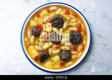 Bohneneintopf mit Schwarzpudding, Paprika und Kartoffeln. Tisch mit Draufsicht und Dekoration. Stockfoto