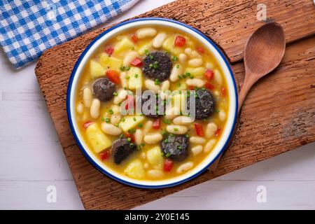 Bohneneintopf mit Schwarzpudding, Paprika und Kartoffeln. Tisch mit Draufsicht und Dekoration. Stockfoto