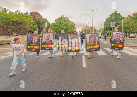 Haifa, Israel - 01. September 2024: Menschen marschieren auf der Straße mit Plakaten der sechs Geiseln, die in Gaza getötet wurden, Teil eines Abends der Empörung r Stockfoto