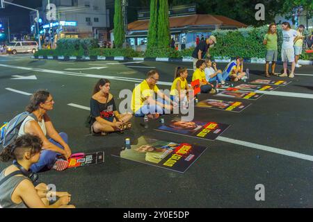 Haifa, Israel - 01. September 2024: Menschen sitzen auf der Straße mit Plakaten der sechs Geiseln, die in Gaza getötet wurden, Teil eines Abends der Empörung Stockfoto