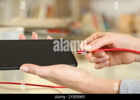 Nahaufnahme einer Frau, die das Ladegerät zu Hause an das Telefon anschließt Stockfoto