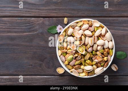 Mit und ohne Schale gefüllte weiße Schüssel mit Pistazien auf einem dunklen hölzernen rustikalen Tisch Stockfoto