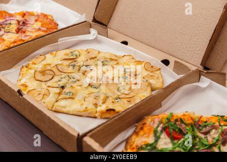 Verschiedene Pizzen in Lieferboxen, Birnen- und Blauschimmelpizza, die serviert werden kann. Stockfoto