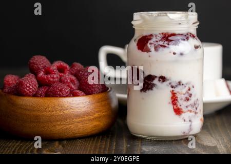 Frischer Milchjoghurt mit ganzen frischen Himbeeren, ein Glas mit Himbeeren und frischer Joghurt aus Kuhmilch Stockfoto